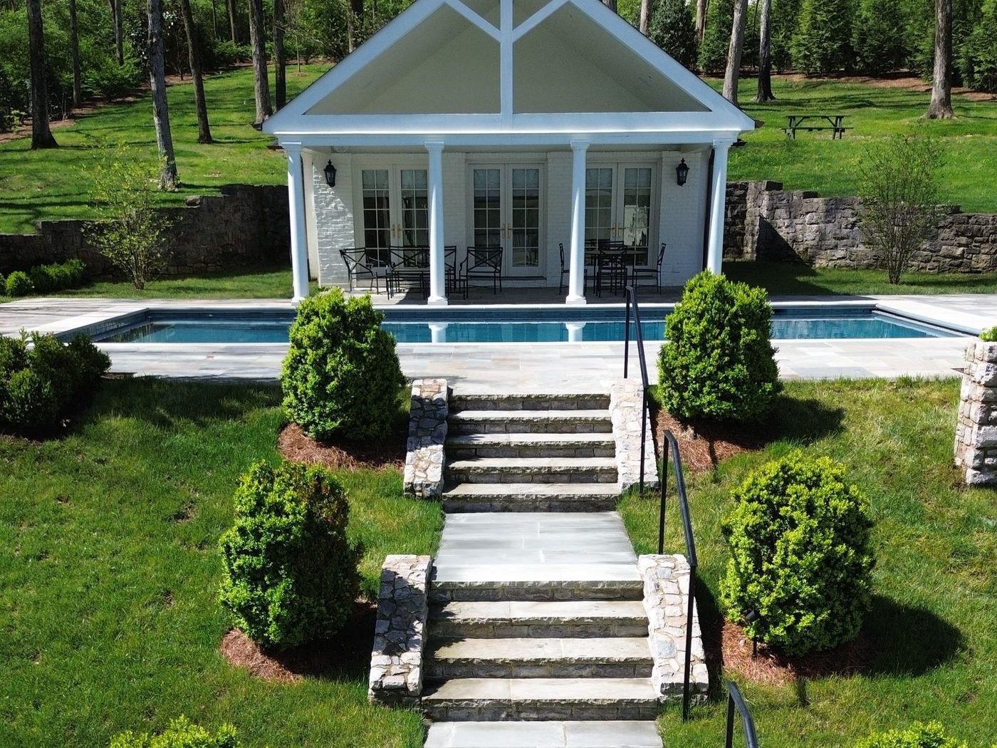 Estate pool house with stone terraces and landscaped steps