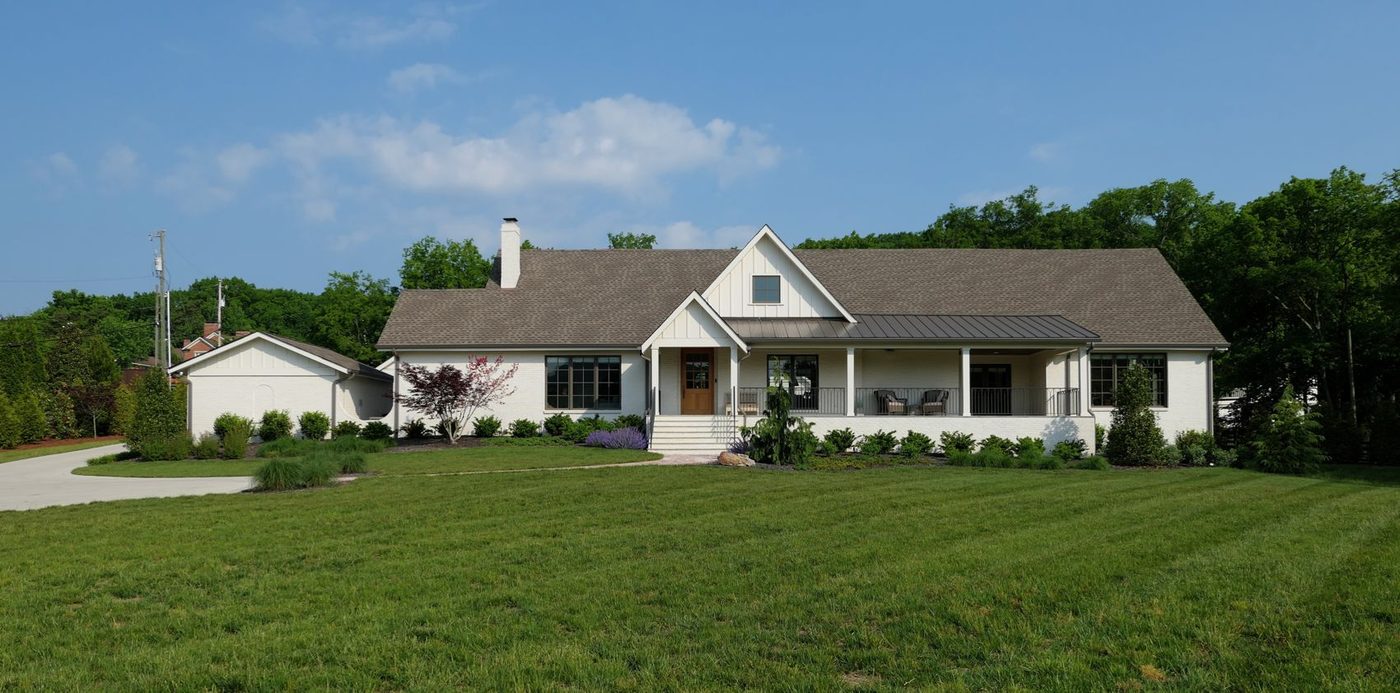 Custom ranch-style home with covered porch and landscaped lawn